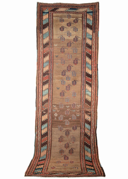 19th century Kurdish runner featuring a pattern of sparse and asymmetrically organized botehs in dark and light blues, apricot, and madder on a plush, variegated camel field. Abstracted figures and shapes which are likely the weaver and a rendition of bats or birds can be found near the center. A colorful main border of wide diagonal stripes more commonly found in Kurdish bag faces energizes the composition and adds additional distinction. 