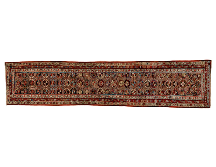 This Malayer runner was handwoven early 20th century. allover geometric design of eight pointed stars that seem to float above alternating diamonds. With patinated but lively with accents of ivory and chocolate. It is framed by thin lines of solid color and three thin borders of floral meanders each on a different color ground. There is some oxidation in the browns that give it a tile like appearance. Wonderful use of color and contrast build a skillful executed mosaic