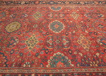 It features a dense and rhythmic allover pattern of palmettes, rosettes, and roving vinery set against a richly saturated madder red field.&nbsp;Lush floral clusters and shield-like medallions in blues, golds, ivory, and greens are symmetrically arrayed across the surface, producing a mesmerizing, layered composition.&nbsp;The deep indigo border is animated with bold palmettes and angular vine scrolls, grounding the exuberant interior with contrast and balance. This carpet’s large format and harmonious pale