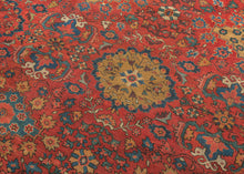 It features a dense and rhythmic allover pattern of palmettes, rosettes, and roving vinery set against a richly saturated madder red field.&nbsp;Lush floral clusters and shield-like medallions in blues, golds, ivory, and greens are symmetrically arrayed across the surface, producing a mesmerizing, layered composition.&nbsp;The deep indigo border is animated with bold palmettes and angular vine scrolls, grounding the exuberant interior with contrast and balance. This carpet’s large format and harmonious pale