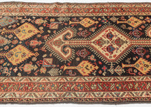 This stunning rug features a vertical medallion design on a deep indigo blue field. The field is filled with a fantastical world of various trees and plant forms surrounded by all types of animals. There are multiples types of birds including peacocks as well as two human figures near the bottom of the composition. The world is wonderfully painted with contrasting tones of reds, yellow, ivory, and aubergine. Lori rug