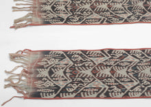 A striking West Timor cotton ikat featuring rhythmic ancestral and vegetal motifs arranged in a vertical progression. Deep brown-black and soft ivory form the primary contrast, accented by subtle coral and indigo details that animate the surface.

The repeating abstracted figural forms and branching motifs reflect Timorese ceremonial weaving traditions, executed in warp ikat with characteristic feathered edges. Finished with traditional fringe and side bindings.