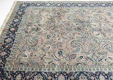 This Mashad rug was handwoven during the middle of the 20th century.

It features an allover design that radiates from a central axis with mirrored sprays of stylized palmettes, saz leaves and rosettes in shades of icy blue, indigo, shell pink and ivory on a silver ground. Nicely framed by a perfectly reconciled main border of palmettes on a midnight blue ground. The original ground color was a purple tone that was not color fast and has perfectly faded into a cool silver tone which is very uncommon in vint