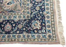 This Mashad rug was handwoven during the middle of the 20th century.

It features an allover design that radiates from a central axis with mirrored sprays of stylized palmettes, saz leaves and rosettes in shades of icy blue, indigo, shell pink and ivory on a silver ground. Nicely framed by a perfectly reconciled main border of palmettes on a midnight blue ground. The original ground color was a purple tone that was not color fast and has perfectly faded into a cool silver tone which is very uncommon in vint