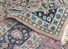 This Mashad rug was handwoven during the middle of the 20th century.

It features an allover design that radiates from a central axis with mirrored sprays of stylized palmettes, saz leaves and rosettes in shades of icy blue, indigo, shell pink and ivory on a silver ground. Nicely framed by a perfectly reconciled main border of palmettes on a midnight blue ground. The original ground color was a purple tone that was not color fast and has perfectly faded into a cool silver tone which is very uncommon in vint