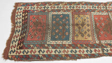 It features vertically stacked boxes, each filled with scattered diamonds across saturated grounds of color. The diamond motifs serve both as protective emblems and as a kind of visual chant, anchoring the eye while the overall composition moves with the spontaneity of Kurdish village life. The palette is classic and earthy: madder red, saffron gold, deep indigo, and teal, with ivory highlights animating the zigzag borders.