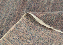 This unusual Chinese rug reflects an inventive approach to material reuse and modern design. Its oval shape and softly variegated surface are woven from a blend of reclaimed yarns to create a subtle, almost painterly texture that shifts between muted mauve, slate, and mineral blue tones. The fine mosaic of color and understated abstraction evoke the spirit of Art Deco modernism while remaining deeply tactile and organic