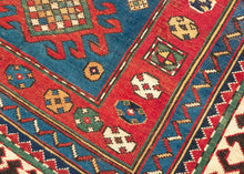 This Kazak was handwoven during the early 20th century in the southwest Caucasus.

A beautifully drawn Kazak featuring a chain of hooked diamond medallions on a vibrant sky-blue field. Each medallion is filled with either concentric diamonds or rubik's cube like grid in ivory, saffron, madder red, and deep indigo. Scattered rosettes and small geometric motifs animate the field, creating a lively rhythm. The border system is classic and powerful with an ivory “ram’s horn” outer border that encloses a richly 