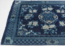 A luminous Ningxia rug woven in a sophisticated monochrome palette of deep indigo, sky blue, and soft ivory. At the center, a roundel of interlocking fretwork and stylized lotus motifs anchors the composition, surrounded by a generous spray of peonies that bloom across the field in balanced symmetry. The drawing is crisp yet fluid, displaying the gentle curvature and painterly shading characteristic of Ningxia weaving.

The border system is exceptionally rich with meandering key-fret bands, lattice grounds,