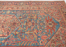 It features an atypical medallion-and-field composition centered around a coral octagonal medallion filled with angular palmettes and rosettes. The surrounding field is rendered in a softly abrashed sky-to-steel blue with scrolling vinery, serrated leaves, and stylized blossoms. The spandrels echo the motif density of the field yet shift toward coral and salmon tones that warm the overall composition. In another uncommon twist, a vertical line of single rosettes connects the spandrels, giving the piece a ba