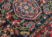A finely drawn Jozan rug with a deep midnight-blue field filled with scrolling vines, palmettes, and delicate floral motifs surrounding a compact central medallion. The lively botanical design unfolds symmetrically across the field, framed by a richly ornamented red border populated with stylized blossoms and curling tendrils.