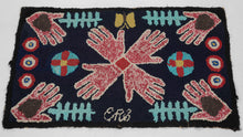 WPA-era American hooked rug from the Southwest US with a central radial motif of stylized hands in red and ivory on a navy ground, surrounded by geometric symbols and a small maker’s initial at the lower edge.