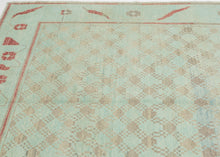 A wonderfully unusual handwoven rug with a soft aqua ground and an intricate allover network of small geometric forms in taupe, gray, and faded blue. The dense central field is surrounded by a much more open border populated with quirky, almost pictographic motifs in brick red and charcoal. 