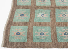 A wonderfully graphic vintage latch-hook rug with a repeating grid of aqua panels, each centered by a playful abstract motif in soft blush, salmon, and deep blue. The warm brown ground gives the composition structure while allowing the almost cellular, biomorphic forms to float across the surface.