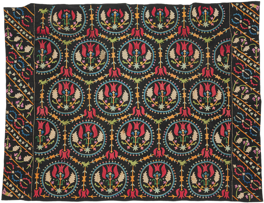 This embroidered textile is a well-preserved example of late Ottoman Armenian domestic needlework, likely produced in the town of Marash (modern-day Kahramanmaraş, Turkey) at the turn of the 20th century.  

The embroidery is executed in silk floss using satin and couching stitches across a black cotton ground.  It features concentric floral medallions, stylized birds and serrated leaves in lively blues, greens, red, pink, purple, yellow and ivory. Notably, two guardian-like anthropomorphic figure