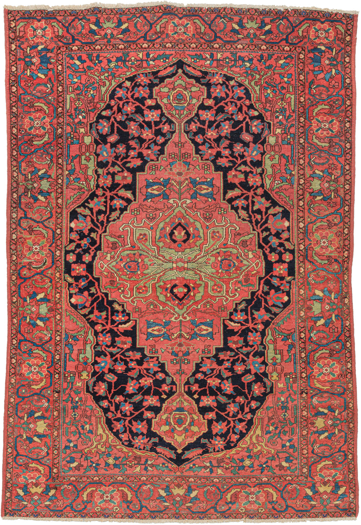 Antique Malayer area rug featuring an ornate medallion with a pistachio green central motif on a soft and elegant red ground. The same pale red is also utilized in the ground of the cornices and main border which magnifies the secondary tones of blue, yellow, aubergine, and pistachio and gives the piece a subtle sophistication. The biggest departure can be found in the navy ground of the field which breaks up the composition nicely. 