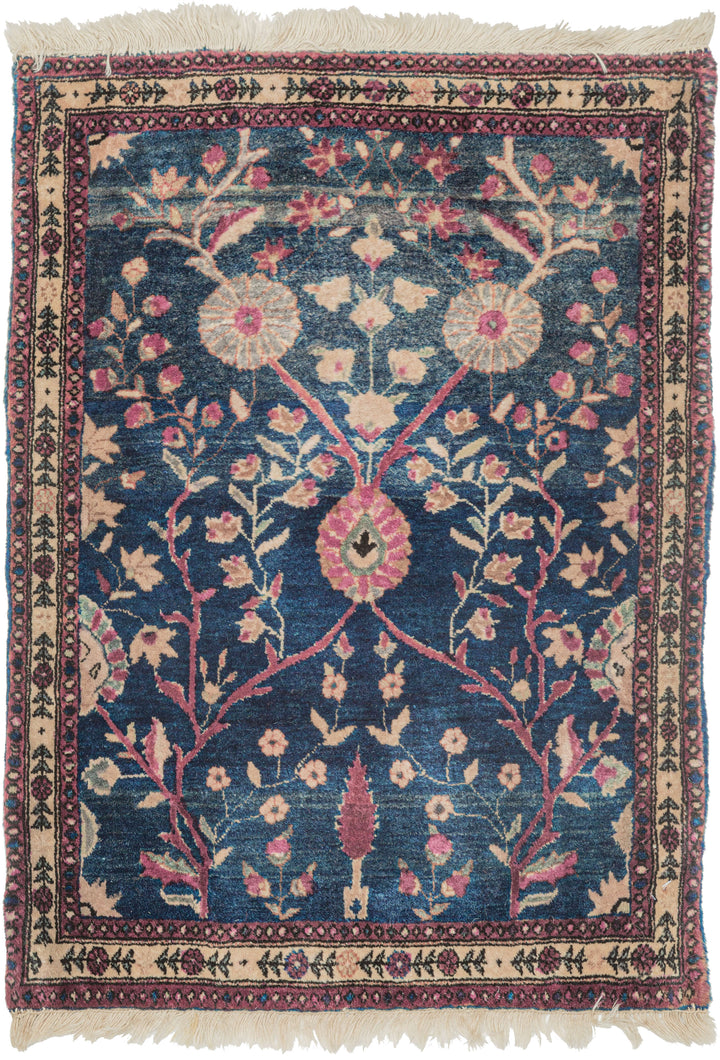 This Mohajeran Sarouk was handwoven during the first quarter of the 20th century. 

It features an imaginative tree of life design of a small cypress flanked by two whimsically intersecting trees bearing palmette-shaped 