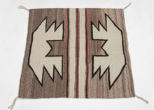 This Navajo rug was handwoven in the southwest United States during the 2nd quarter of the 20th century.

A beautifully balanced small-format Navajo weaving, showcasing bold symmetrical motifs rendered in a ground of hand-spun, natural wool tones. Graphic stepped&nbsp;forms float against soft variegated browns, mirror one another on each side of a classic banded center that is accentuated by&nbsp;warm red accents.