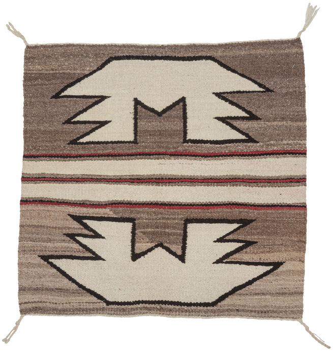 This&nbsp;Navajo rug was handwoven in the southwest United States during the 2nd quarter of the 20th century.

A beautifully balanced small-format Navajo weaving, showcasing bold symmetrical motifs rendered in a ground of hand-spun, natural wool tones. Graphic stepped&nbsp;forms float against soft variegated browns, mirror one another on each side of a classic banded center that is accentuated by&nbsp;warm red accents.