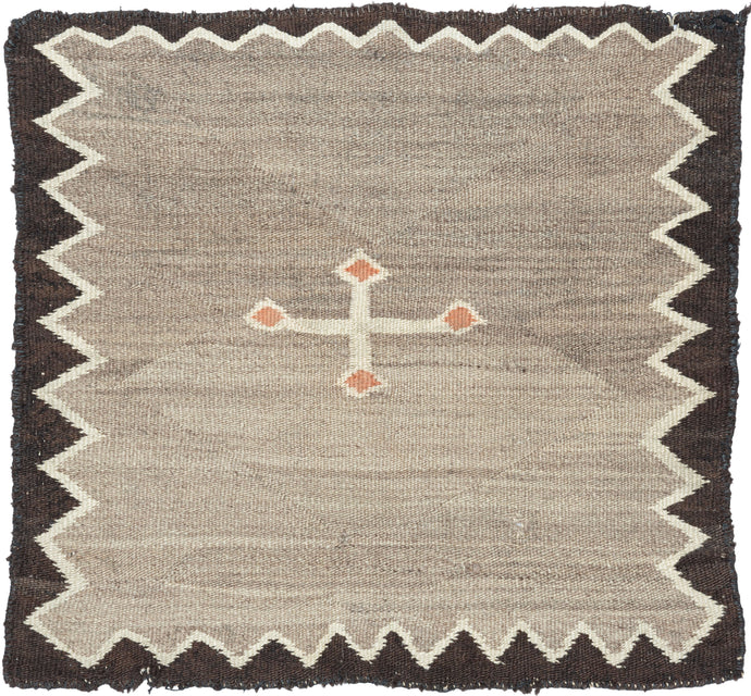 Antique Navajo gray small kilim composed of single slight off-centered ivory cross with orange nodes on a heathered gray field. Framed by thin ivory zigzag and solid brown perimeter.