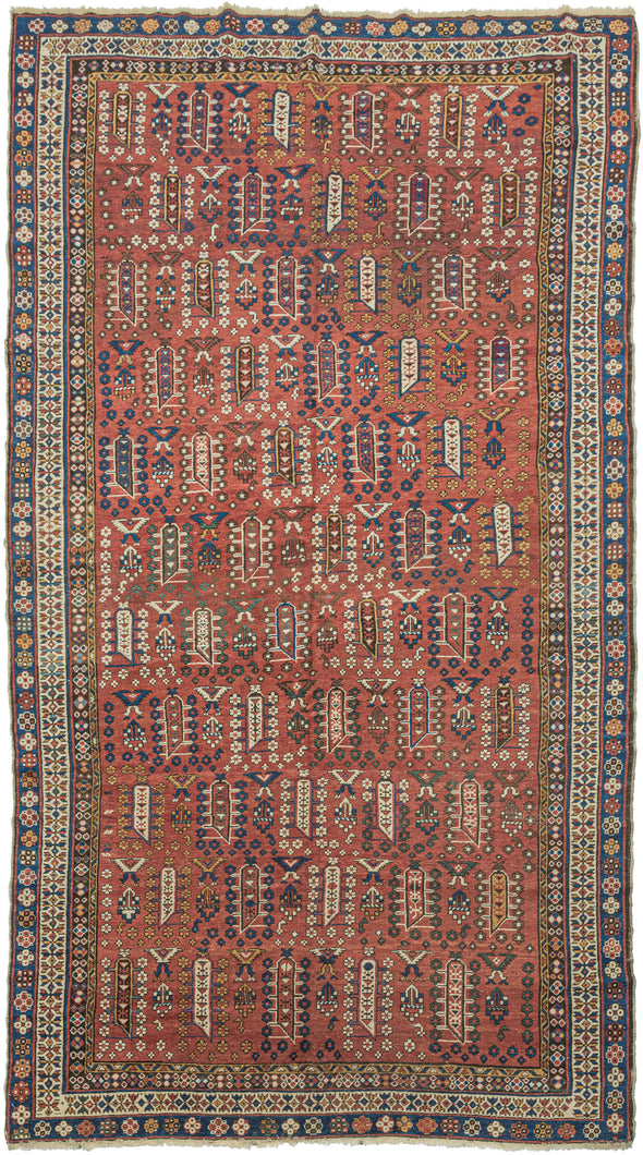 This Shirvan was handwoven during the early 20th century in the Eastern Caucasus.

It features an allover design in diagonal rows on an earthy red ground. The field is composed of tree-like forms each surrounded by rosettes. In between each tree-like form are a geometric flower and a form with opposing bird-like figures.