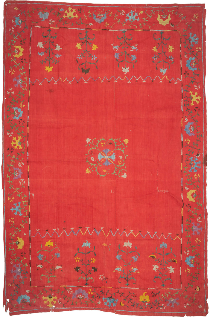 This Suzani was handmade during the early 20th century in Uzbekistan.

This suzani is composed of central floral motif embroidered in silk on an open red cotton field. Flanked by vibrant multi-tiered blossoming flowers to the right and left and framed by a lively floral meander. A multitude of colors are used for the embroidery, including turqoise, green, white, yellow, and purple.