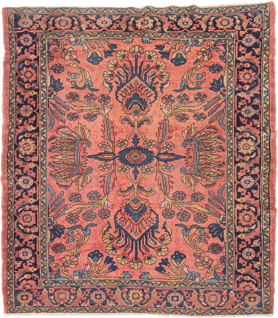 This classic Lilihan rug features a graphic medallion in navy, turquoise, red, and gold on a peach-pink ground. The all-encompassing medallion is composed of ornate curvilinear floral sprays and is freely spaced. Framed by a meandering palmette border with a midnight ground.