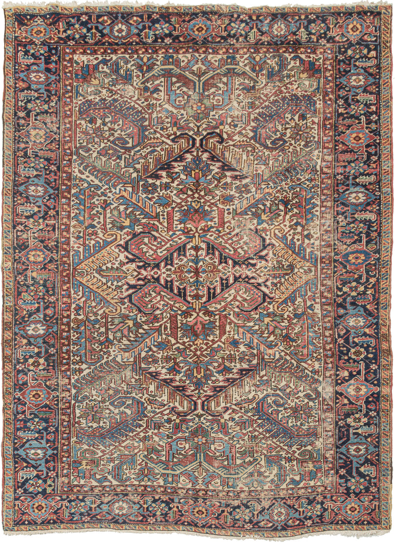 This Ivory Heriz Rug features an allover design of scrolling two-tone leaves in a variety of color combinations on a rare ivory ground. All-over designs are less common on Heriz rugs which most often feature large central medallions. Framed by a main border that is composed of rosettes and alternating palmettes on midnight blue ground.