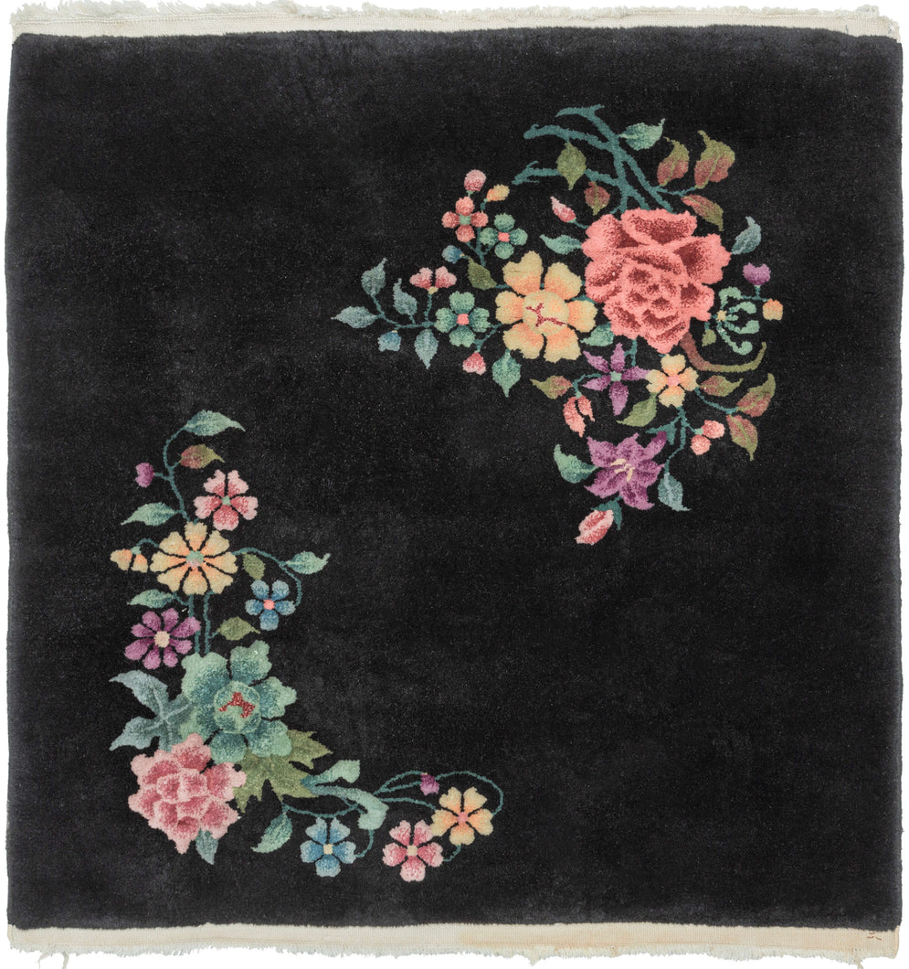 This Art Deco rug was handwoven in Tientsin, China during the second quarter of the 20th century.   This sumptuous Deco rug features a detailed naturalistic design of two distinct blossoming branches on a black ground. The eye-catching design features peonies, chrysanthemums, fruit blossoms among flowers rendered in greens, orange, pink, blue and purple. The flowers really pop against the true black ground.