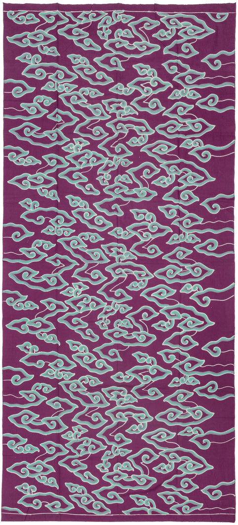 This vintage batik textile is showcases the classic mega mendung or cloud motif with graphic flair and vivid contrast. Floating across a rich purple ground, the swirling turquoise cloud forms evoke movement and energy, like wind-drawn currents or rising mist. The stylized clouds—long associated with spiritual transcendence and protection in Javanese design—feel newly alive in this modern palette.

The batik technique here is cap (stamped) or possibly hand-drawn tulis with a freeform flow, lending the d