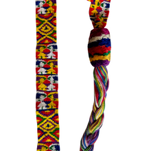A vibrant woven cinta from Zunil, Quetzaltenango, Guatemala. This long headdress band is brocaded with repeating multicolored motifs, including geometric diamonds and stylized human figures in bright yellow, green, red, and white against a richly patterned ground. The ends finish in twisted multicolored tassels, typical of Zunil weaving.

Cintas are among the most distinctive elements of Maya women’s attire. They are wrapped elaborately around the head, creating a striking crown-like headdress, as seen in t