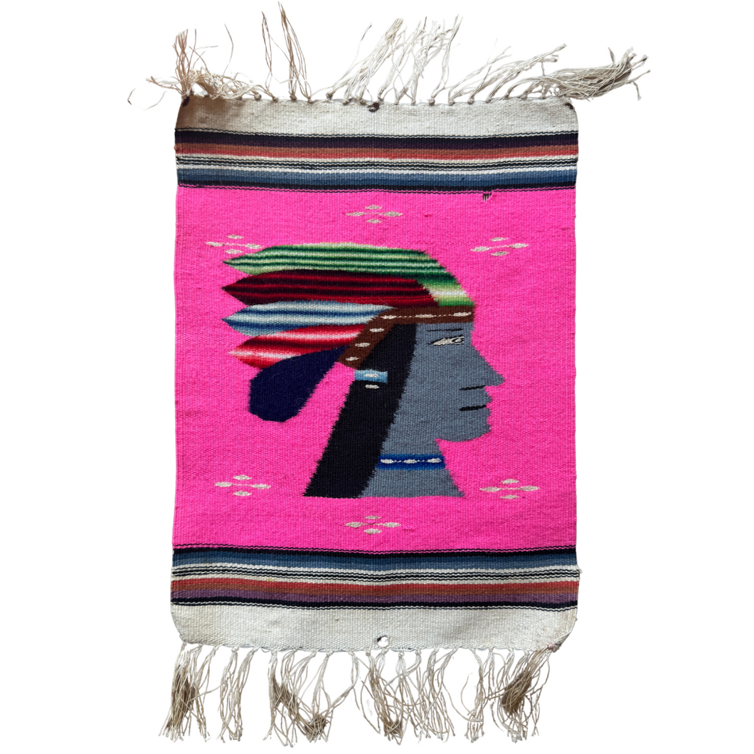 A bold mid–20th century Zapotec pictorial weaving from Oaxaca, Mexico, featuring the profile of a stylized figure in vivid detail. The face, woven in slate grey, is framed by long black hair and a richly patterned striped headdress in green, red, and blue, accented with white. The figure wears a beaded blue necklace, adding further ornament.

