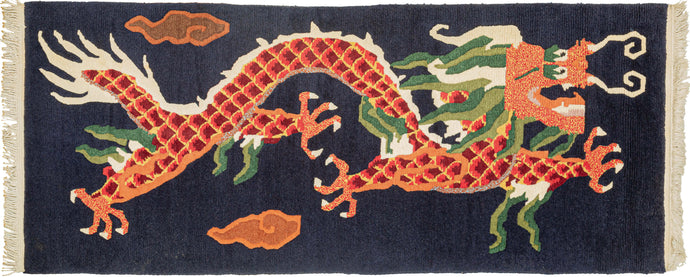 Tibetan carved rug It features a four clawed dragon flying through the clouds. In red, orange and yellow scales with ivory, light and dark green accents that pop against an open navy ground. The claws and face are rendered in red and yellow static and details like the dragon's scales and mane have been hand-carved with a razor adding extra detail and interest
