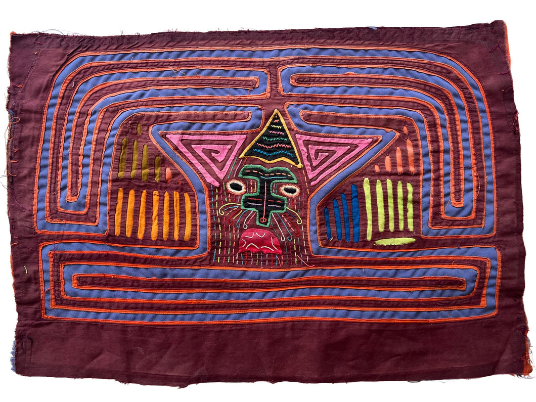 Vintage Mola cloth handmade by the Guna (previously spelled Kuna) people of the San Blas Islands.  Mola is a reverse appliqué technique, similar to the technique used in quilting but using multiple layers of different-colored cloth that are first sewn together before a design is created by cutting away different layers. These cloths are traditionally made in pairs to be worn on the front and back of women's blouses.  This Mola features a strange face. 