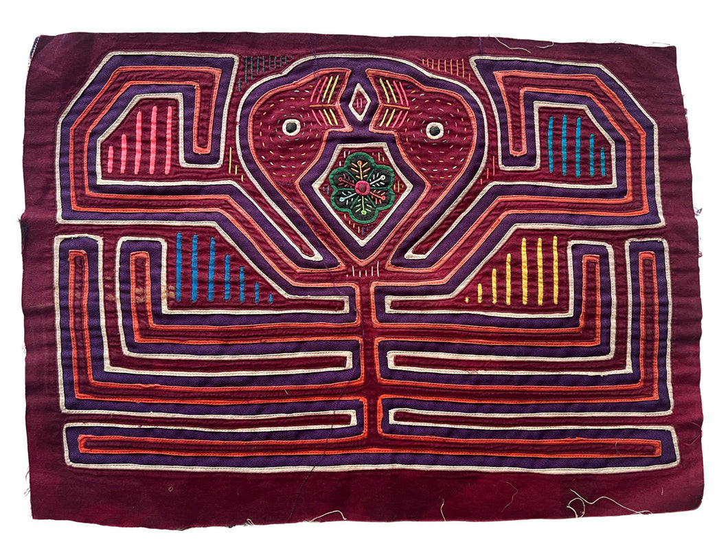 Vintage Mola cloth handmade by the Guna (previously spelled Kuna) people of the San Blas Islands.  Mola is a reverse appliqué technique, similar to the technique used in quilting but using multiple layers of different-colored cloth that are first sewn together before a design is created by cutting away different layers. These cloths are traditionally made in pairs to be worn on the front and back of women's blouses.  This Mola features a two confronting bird heads.  