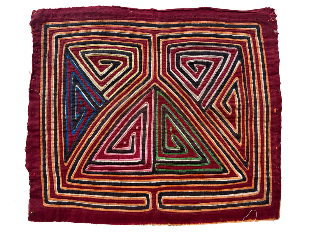 Vintage Mola cloth handmade by the Guna (previously spelled Kuna) people of the San Blas Islands.  Mola is a reverse appliqué technique, similar to the technique used in quilting but using multiple layers of different-colored cloth that are first sewn together before a design is created by cutting away different layers. These cloths are traditionally made in pairs to be worn on the front and back of women's blouses.  This Mola features a geometric design on a burgundy ground. 