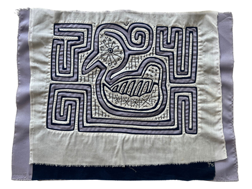 Vintage Mola cloth handmade by the Guna (previously spelled Kuna) people of the San Blas Islands.  Mola is a reverse appliqué technique, similar to the technique used in quilting but using multiple layers of different-colored cloth that are first sewn together before a design is created by cutting away different layers. These cloths are traditionally made in pairs to be worn on the front and back of women's blouses.  This Mola features a bird created from lilac and white fabric.  