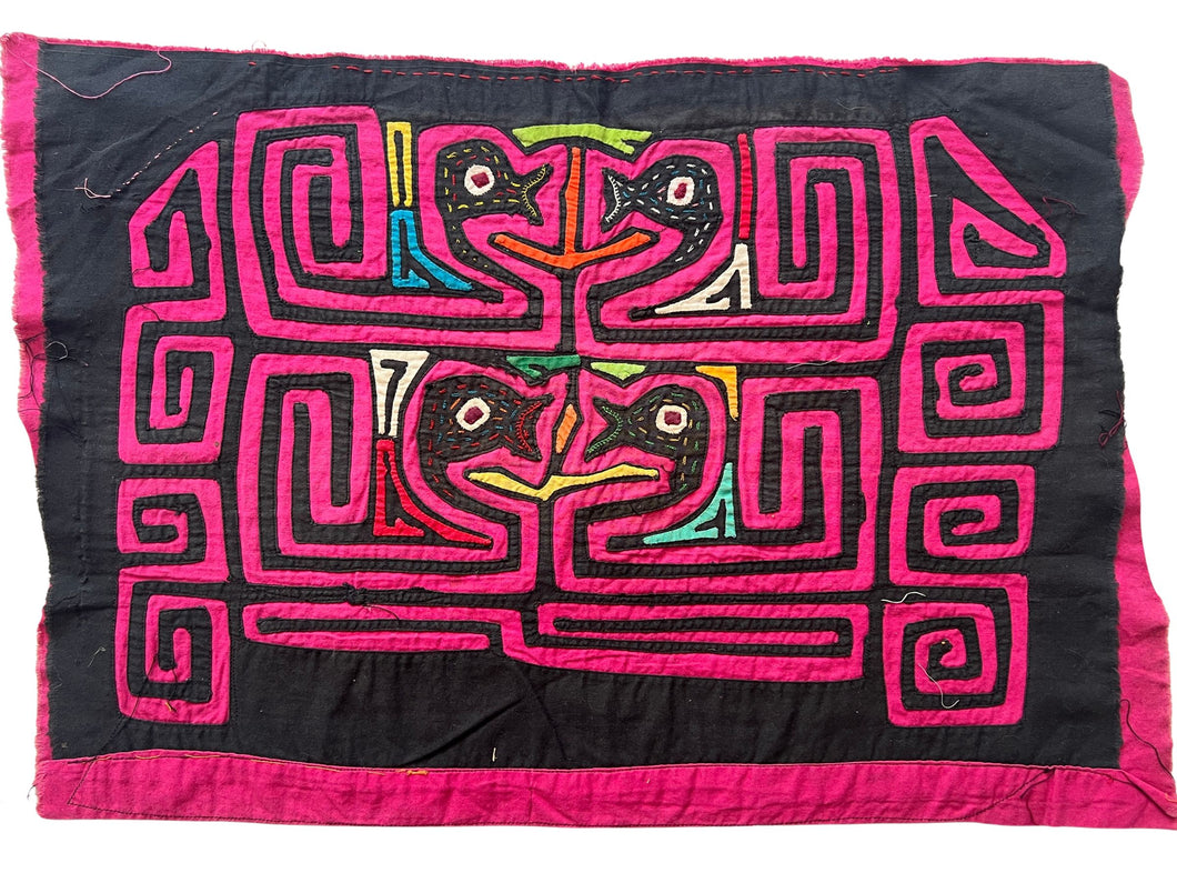 Vintage Mola cloth handmade by the Guna (previously spelled Kuna) people of the San Blas Islands.  Mola is a reverse appliqué technique, similar to the technique used in quilting but using multiple layers of different-colored cloth that are first sewn together before a design is created by cutting away different layers. These cloths are traditionally made in pairs to be worn on the front and back of women's blouses.  This Mola features two pairs of confronting birds heads. 