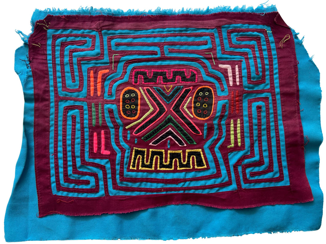 Vintage Mola cloth handmade by the Guna (previously spelled Kuna) people of the San Blas Islands.  Mola is a reverse appliqué technique, similar to the technique used in quilting but using multiple layers of different-colored cloth that are first sewn together before a design is created by cutting away different layers. These cloths are traditionally made in pairs to be worn on the front and back of women's blouses.  This Mola features a skull