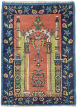 It features a directional gateway formed by an archway that is flanked by two minarets on a rosy red ground and framed by a wide border of flowering vines that showcase three different blue tones. A unique pop of "brat" green is found between the arch and minarets and the two-toned green leaves in the border. The unexpected and energetic color combination make for a fun and funky piece.