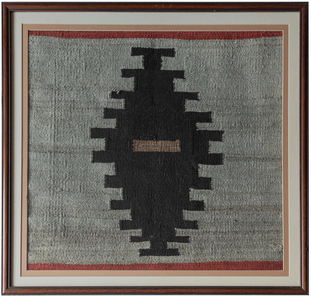 This Navajo rug was woven in the Southwest United States during the 2nd quarter of the 20th Century.

The design is composed of a single black sawtoothed diamond on a heathered gray field. A central sand toned dash and thin blocks of red on the top and bottom add visual interest and dimension. Straightforward yet very moving with a powerful presence. A nice showcase and celebration of Navajo weaving.