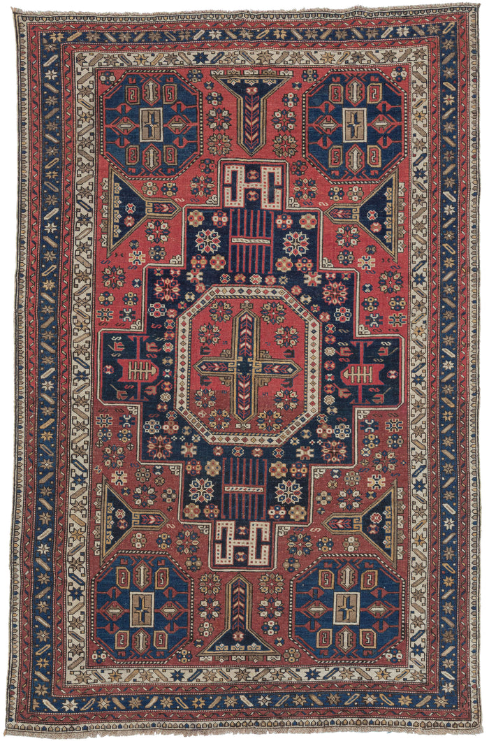 A superb late-19th-century Shirvan whose design vocabulary is more commonly encountered in Shirvan and Kuba Soumaks. The octagonal medallion-and-panel layout, the dense scattering of small rosettes, and the talismanic latch-hook devices all echo the structural geometry of flatwoven Soumak covers which is here translated into a finely knotted pile format with striking clarity. This crossover of motifs is both unusual and highly collectible, reflecting the deep interchange between pile-weaving and flatweave t