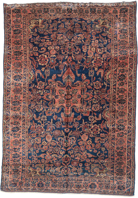 This Sarouk presents a classic, well-balanced composition centered on a bold floral medallion set against a deep indigo-blue field. The drawing is dense yet legible, with scrolling vines, palmettes, and stylized blossoms filling the field in a rhythm that feels controlled rather than crowded.