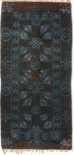 A small Gansu rug woven with a lively arrangement of auspicious symbols against a deep navy field, accented in indigo blue, coral, and muted aubergine. Pairs of stylized bats appear throughout the central field, arranged around endless knots and&nbsp;shou symbols, while interlocking ring motifs line the outer border.

In Chinese decorative arts, the bat is a symbol of good fortune, while the shou character represents longevity and the endless knot suggests continuity and enduring harmony. 