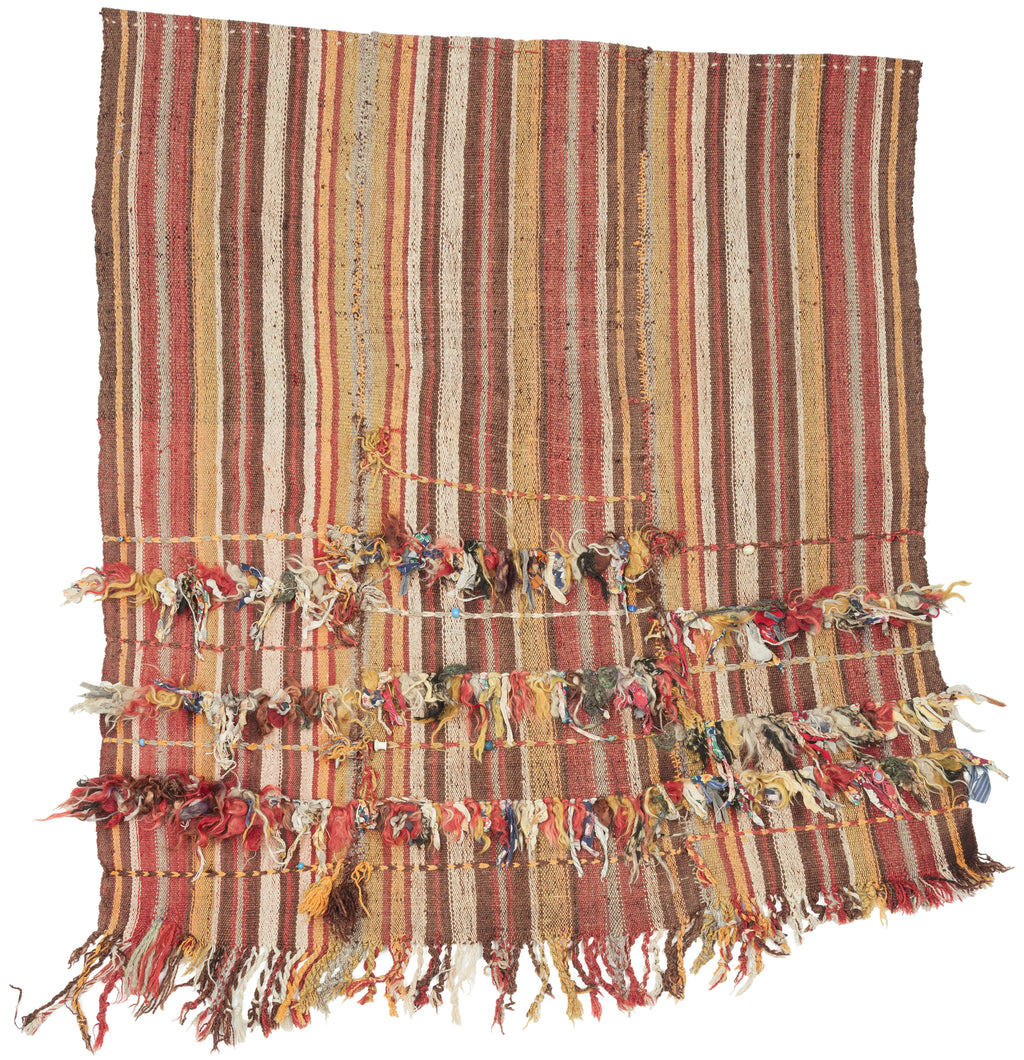 In Anatolian weaving traditions, such additions often carried protective or symbolic meaning. Knotted cords, dangling fibers, and small beads were believed to function as apotropaic elements, intended to ward off the evil eye and protect the household. These expressive embellishments transform the textile from a simple utilitarian weave into a more personal and talismanic object.
