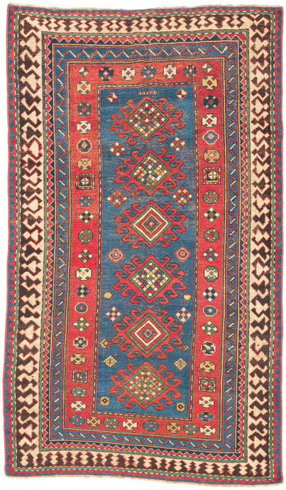 This Kazak was handwoven during the early 20th century in the southwest Caucasus.

A beautifully drawn Kazak featuring a chain of hooked diamond medallions on a vibrant sky-blue field. Each medallion is filled with either concentric diamonds or rubik's cube like grid in ivory, saffron, madder red, and deep indigo. Scattered rosettes and small geometric motifs animate the field, creating a lively rhythm. The border system is classic and powerful with an ivory “ram’s horn” outer border that encloses a richly 