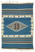 This serape was handwoven in central Mexico during the middle of the 20th century.

A luminous Texcoco serape distinguished by its saturated indigo field and a well articulated central diamond medallion. The stepped, labyrinthine geometry—woven in crisp natural white and deep black creates a powerful visual anchor, while the serrated motifs and butterfly-like accents along the border add nice rhythmic movement.