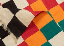 This blanket was likely woven by the Fulani people in Mali during the middle of the 20th century.

It was woven in multiple stripes which have been attached horizontally. It features an eye dazzling checkerboard composed of white, black, red, green, blue and a sunny yellow-orange. Four individual squares around the perimeter are woven with the red-yellow-green tricolor of the Malian flag.

Via The Metropolitan Museum of Art The checkerboard, a basic West African composition, ultimately may derive from