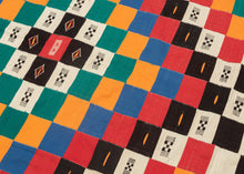 This blanket was likely woven by the Fulani people in Mali during the middle of the 20th century.

It was woven in multiple stripes which have been attached horizontally. It features an eye dazzling checkerboard composed of white, black, red, green, blue and a sunny yellow-orange. Four individual squares around the perimeter are woven with the red-yellow-green tricolor of the Malian flag.

Via The Metropolitan Museum of Art The checkerboard, a basic West African composition, ultimately may derive from