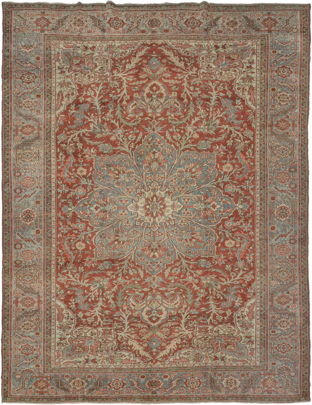 A commanding Heriz rug distinguished by a more ornate, curvilinear drawing than the classic, highly angular Heriz style. The richly saturated red field is centered by a large, radiating medallion with scrolling floral forms that lend fluidity and movement to the composition.